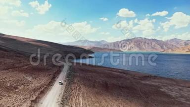 在4x4路的高空，汽车沿着砾石小径驶向<strong>干</strong>旱山区的湖泊。 帕米尔公路丝绸之路